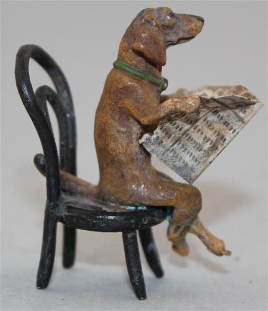 A miniature cold painted bronze model of a seated Dachshund reading a newspaper, in the manner of Franz Bergman, 2in.
